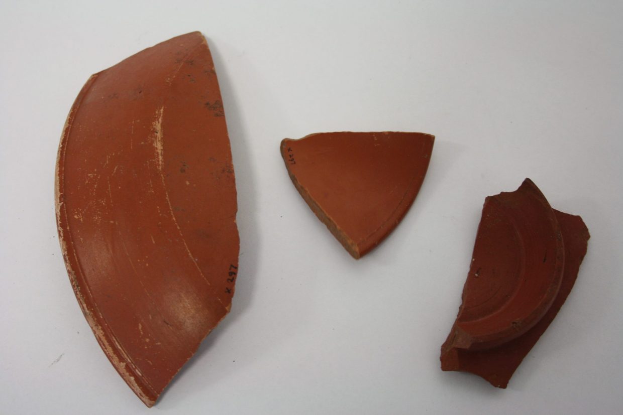 Three pieces of red pottery on a white background.